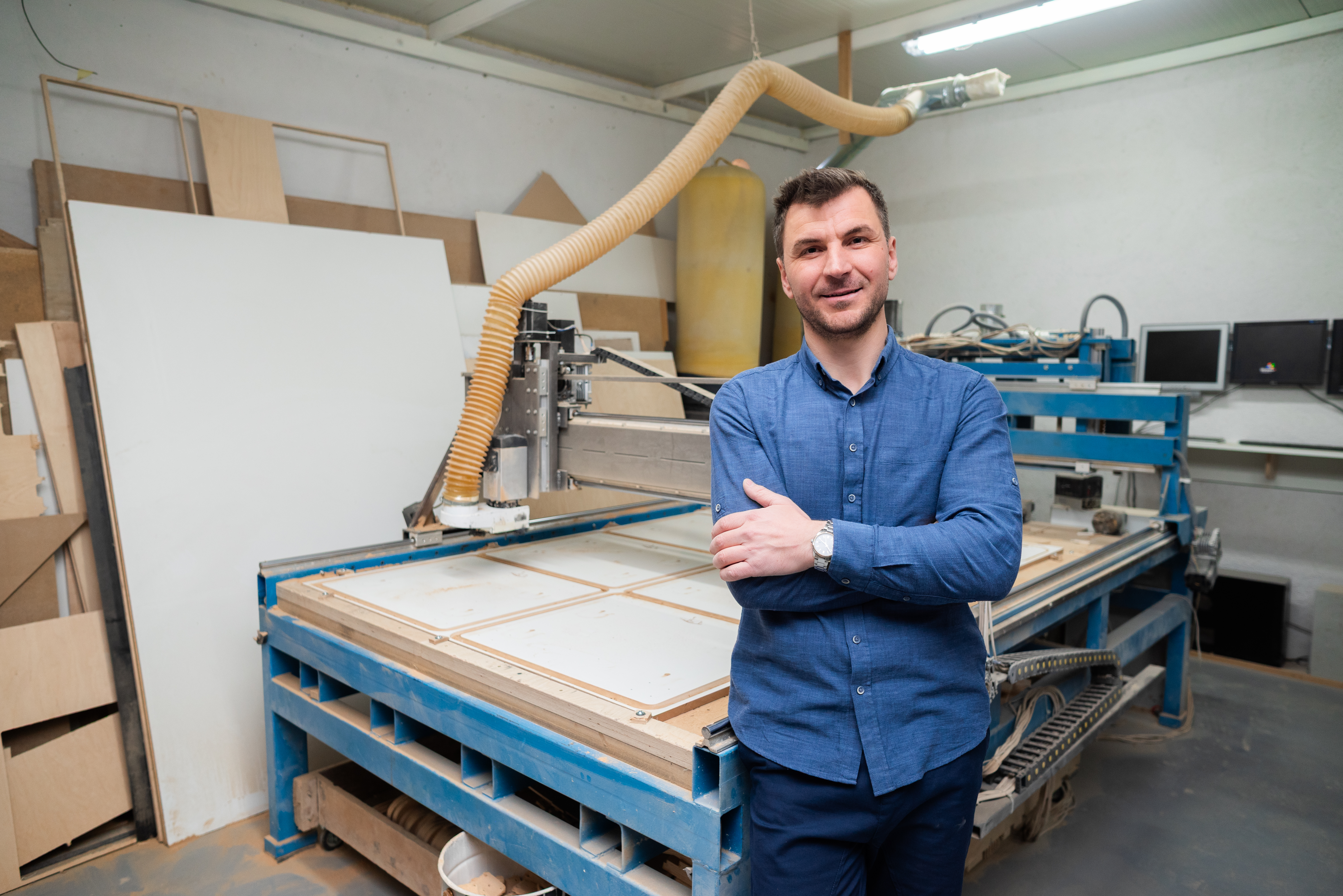 A man stands beside a large woodworking machine in a workshop